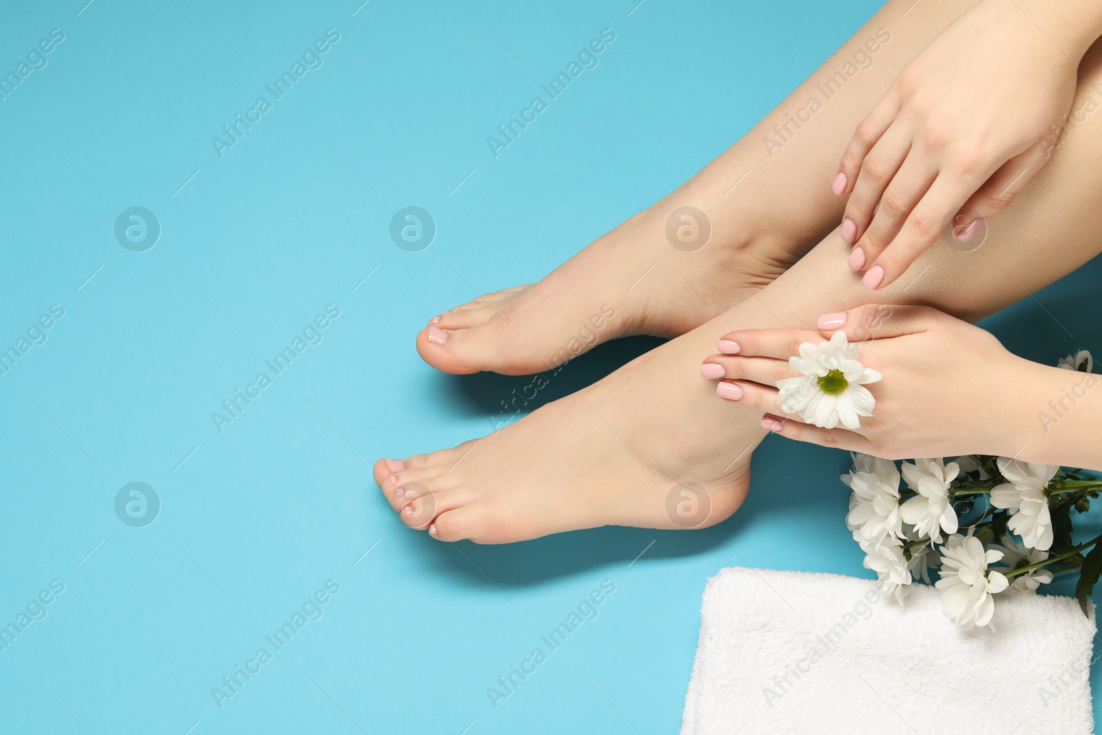 Photo of Woman with neat toenails after pedicure procedure on light blue background, closeup. Space for text