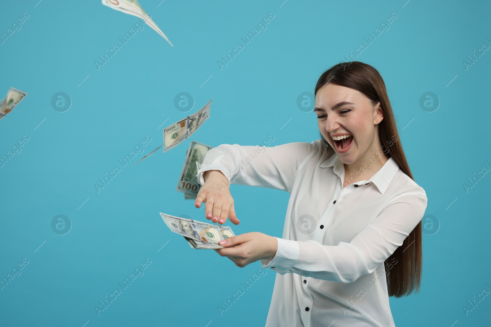 Photo of Happy woman throwing money on light blue background