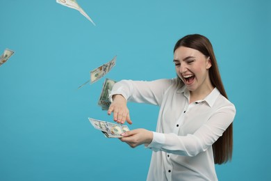 Happy woman throwing money on light blue background