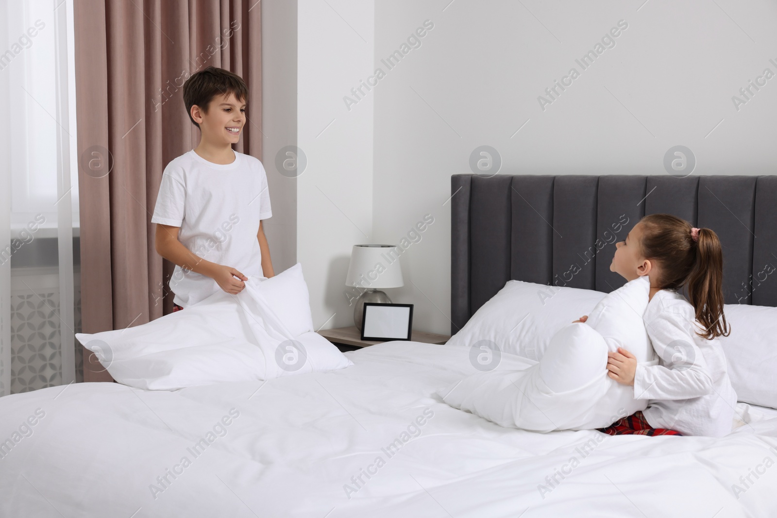 Photo of Brother and sister changing bed linens together in bedroom