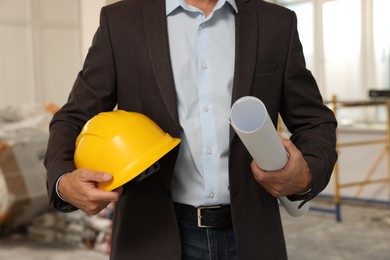 Professional engineer with hard hat and draft indoors, closeup