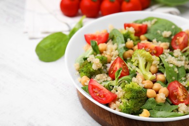 Healthy meal. Tasty salad with quinoa, chickpeas and vegetables on white wooden table, closeup with space for text