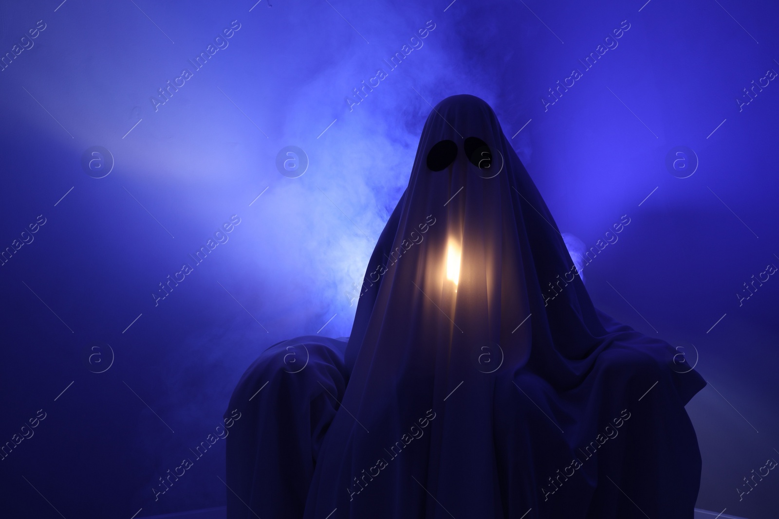 Photo of Creepy ghost. Woman covered with sheet in armchair in blue light, space for text