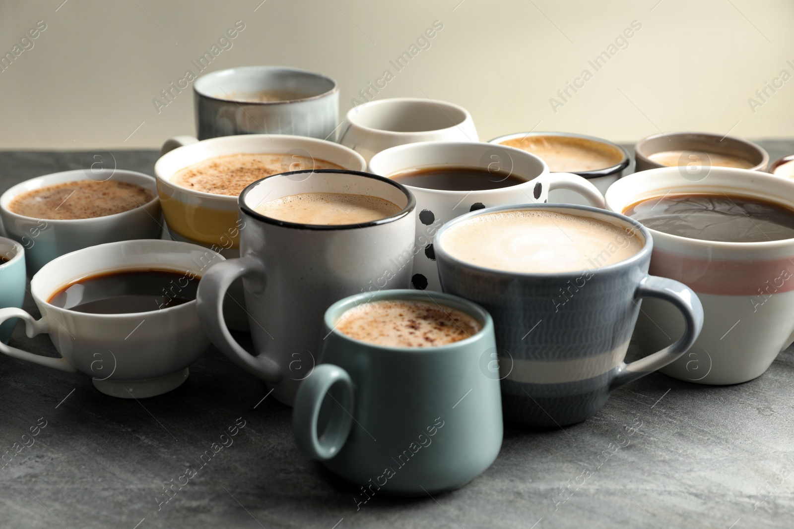 Photo of Many cups of different coffees on slate table