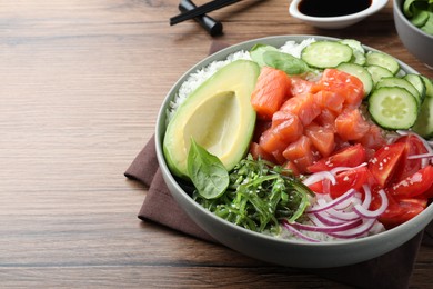 Delicious poke bowl with salmon and vegetables served on wooden table, closeup. space for text