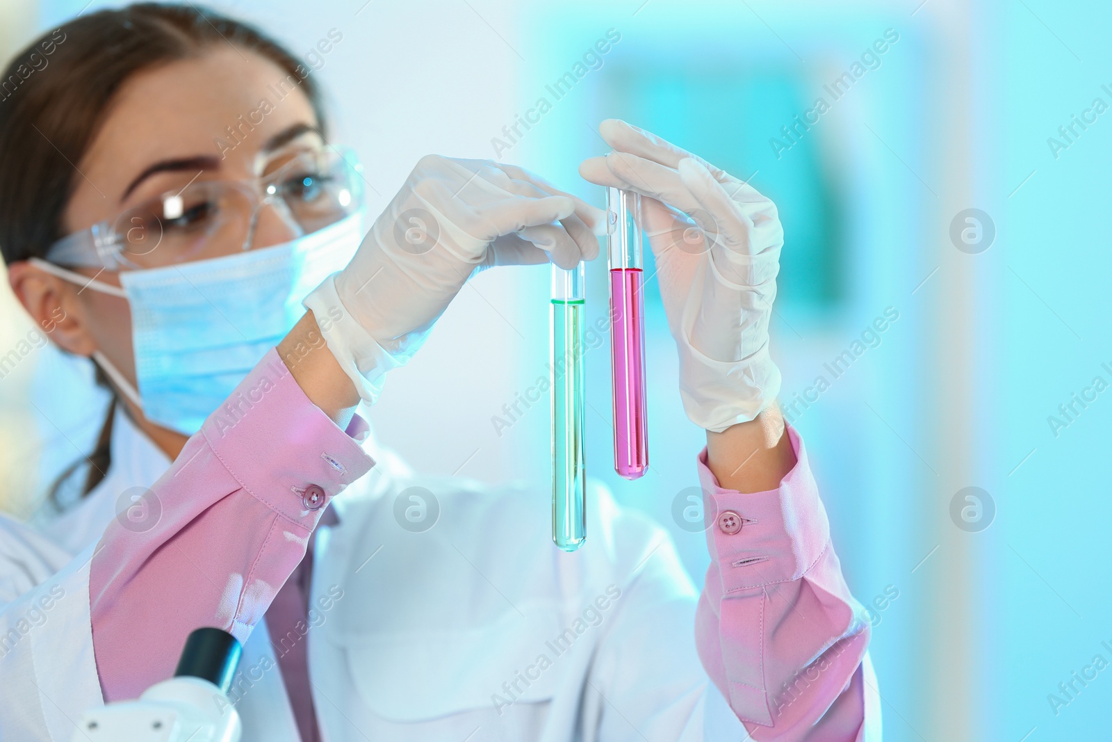 Photo of Young scientist holding test tubes with liquid samples on blurred background. Laboratory analysis