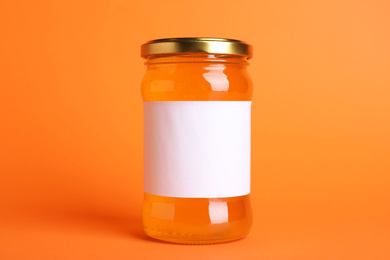 Photo of Jar of organic honey with blank label on orange background. Space for text