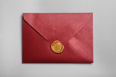 Photo of Red envelope with wax seal on grey background, top view