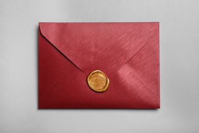 Red envelope with wax seal on grey background, top view