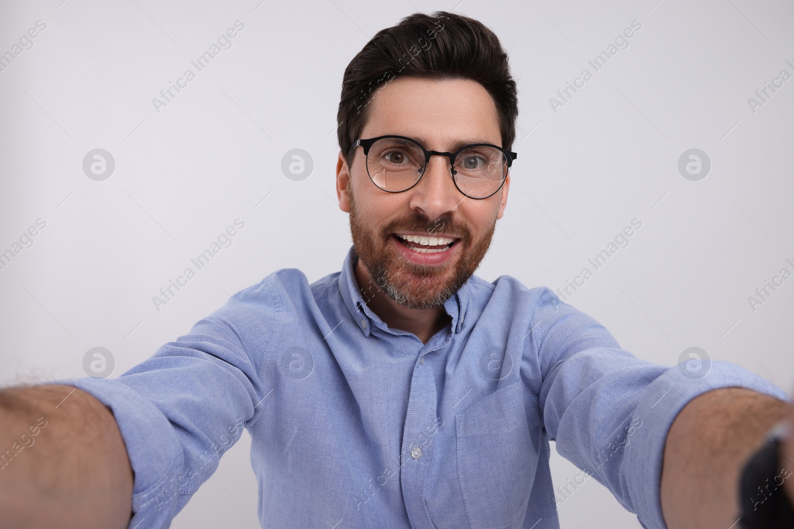 Photo of Smiling man taking selfie on white background