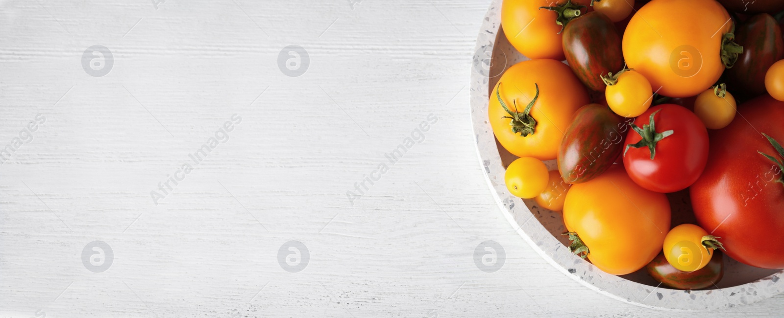 Image of Top view of bowl with fresh tomatoes on white wooden table, space for text. Banner design 