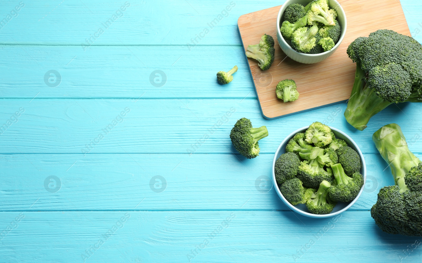 Photo of Flat lay composition of fresh green broccoli on blue wooden table, space for text