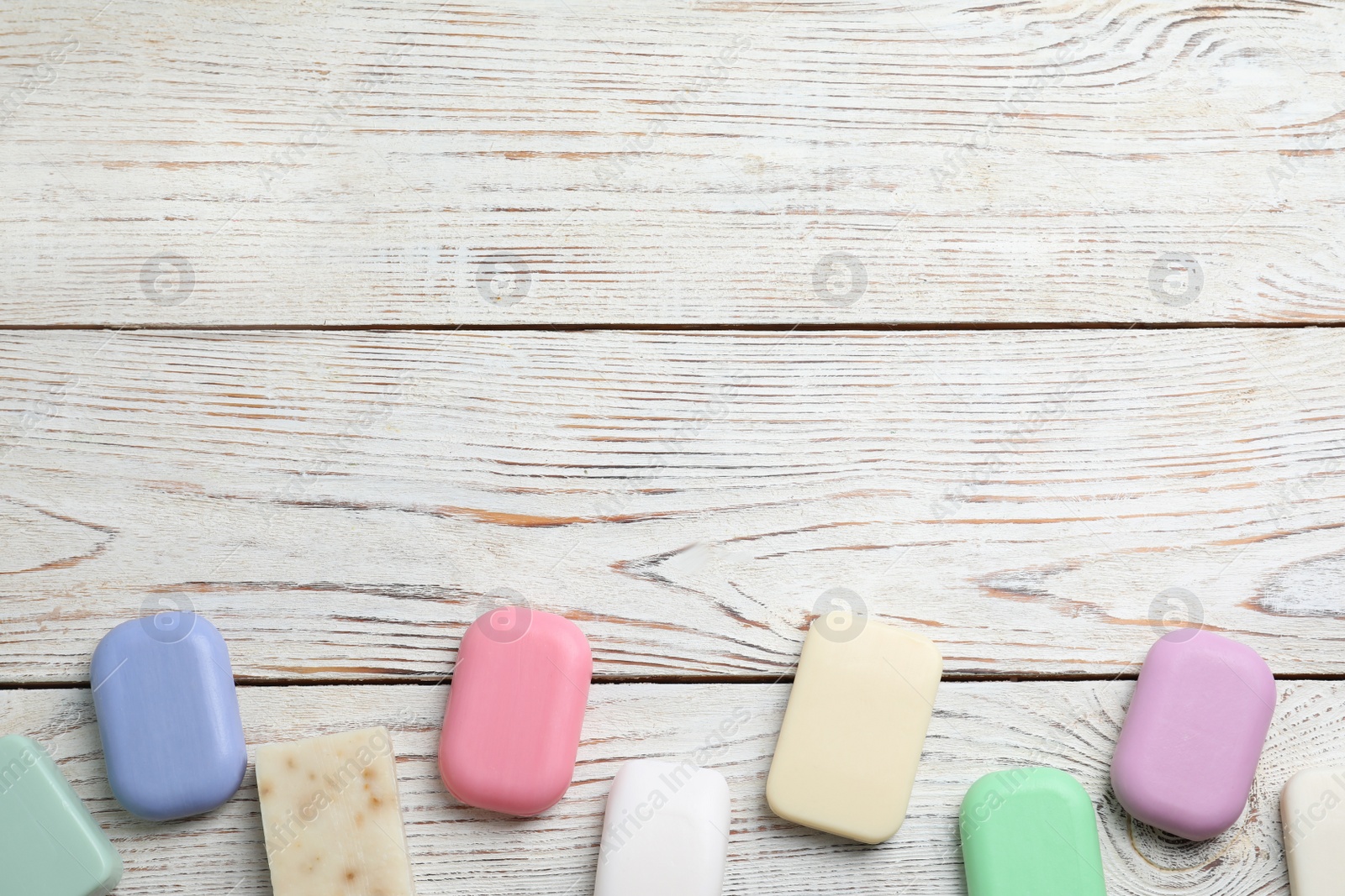 Photo of Many different soap bars on wooden table, flat lay. Space for text