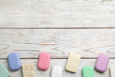 Photo of Many different soap bars on wooden table, flat lay. Space for text
