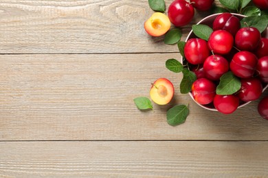 Photo of Fresh ripe cherry plums on wooden table, flat lay. Space for text