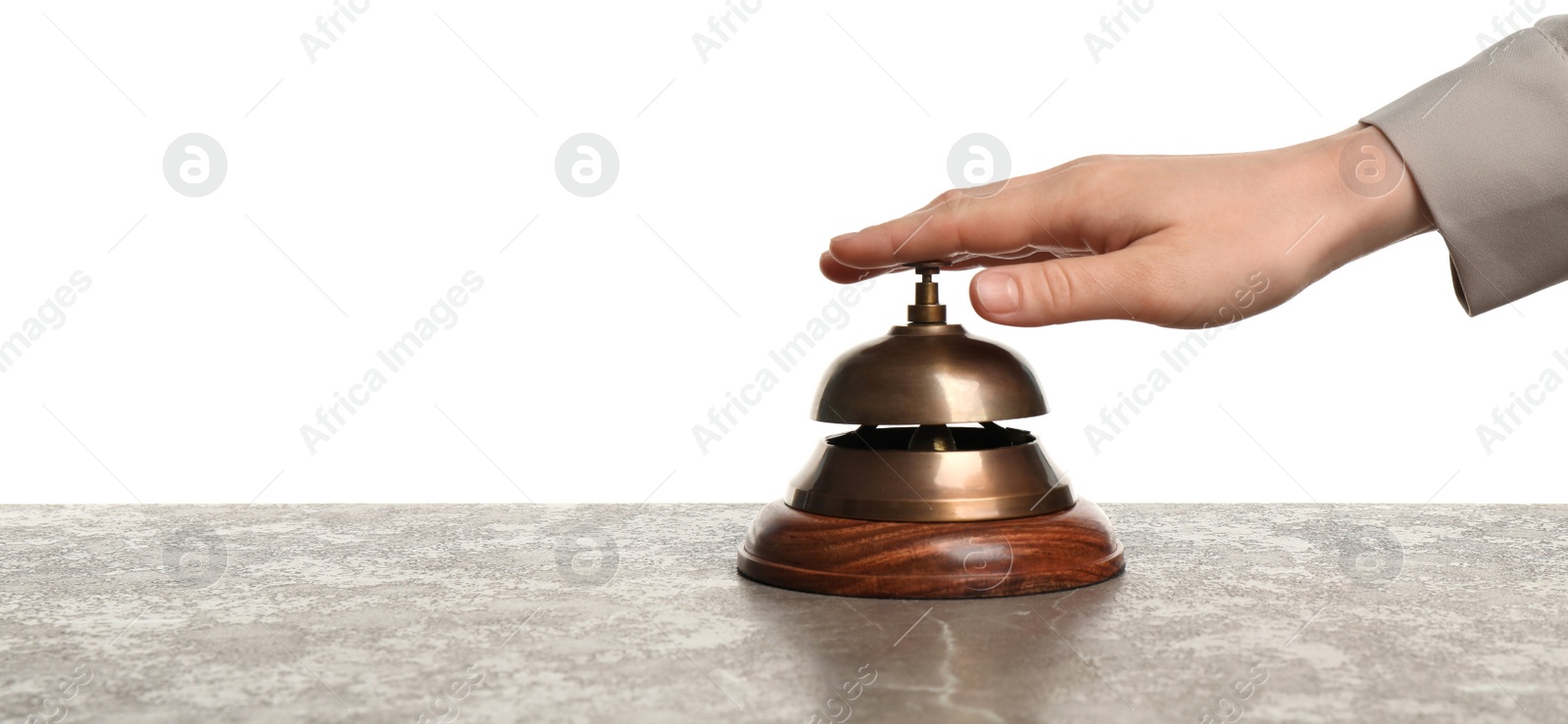 Photo of Woman ringing hotel service bell at grey stone table