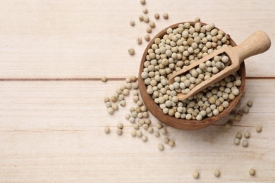 Aromatic spice. White peppers and scoop in bowl on wooden table, top view. Space for text