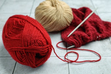 Photo of Soft woolen yarns, knitting and needles on grey tiled background, closeup
