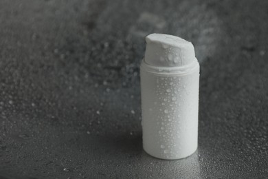 Photo of Moisturizing cream in bottle on dark wet background, closeup. Space for text
