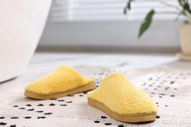 Yellow soft slippers on carpet at home, closeup