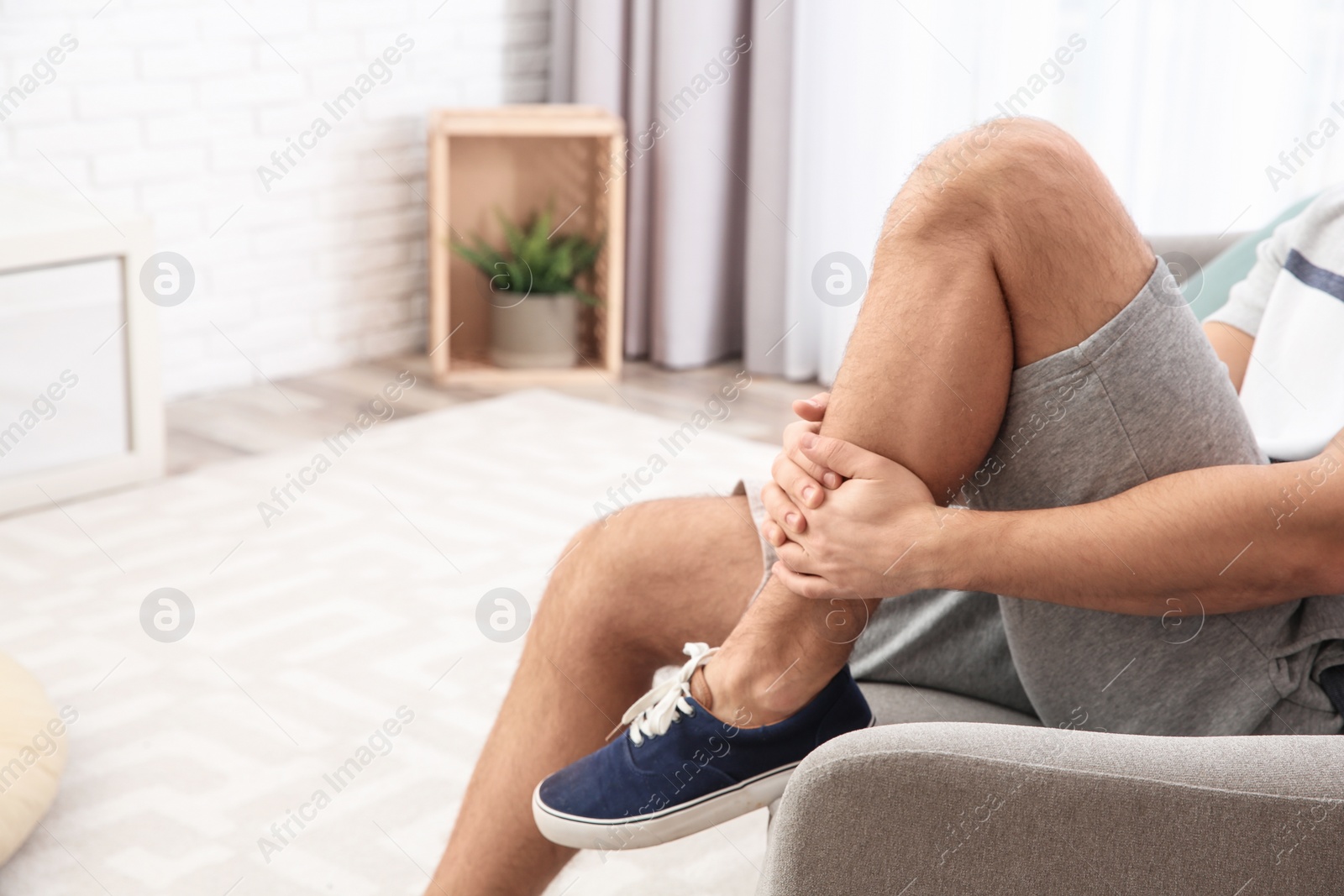 Photo of Man suffering from leg pain at home, closeup. Space for text