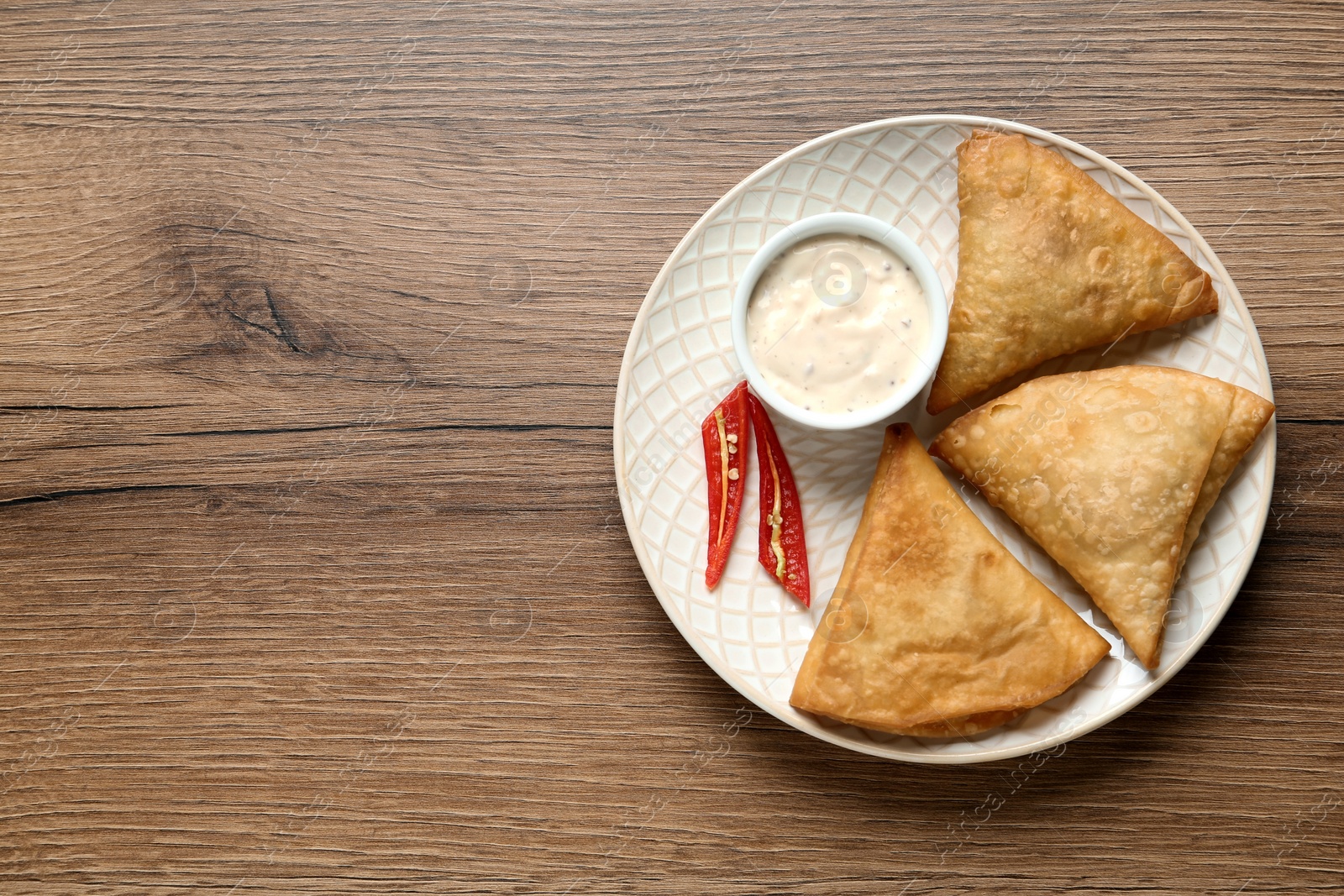 Photo of Fresh delicious crispy samosas served on wooden table, top view. Space for text