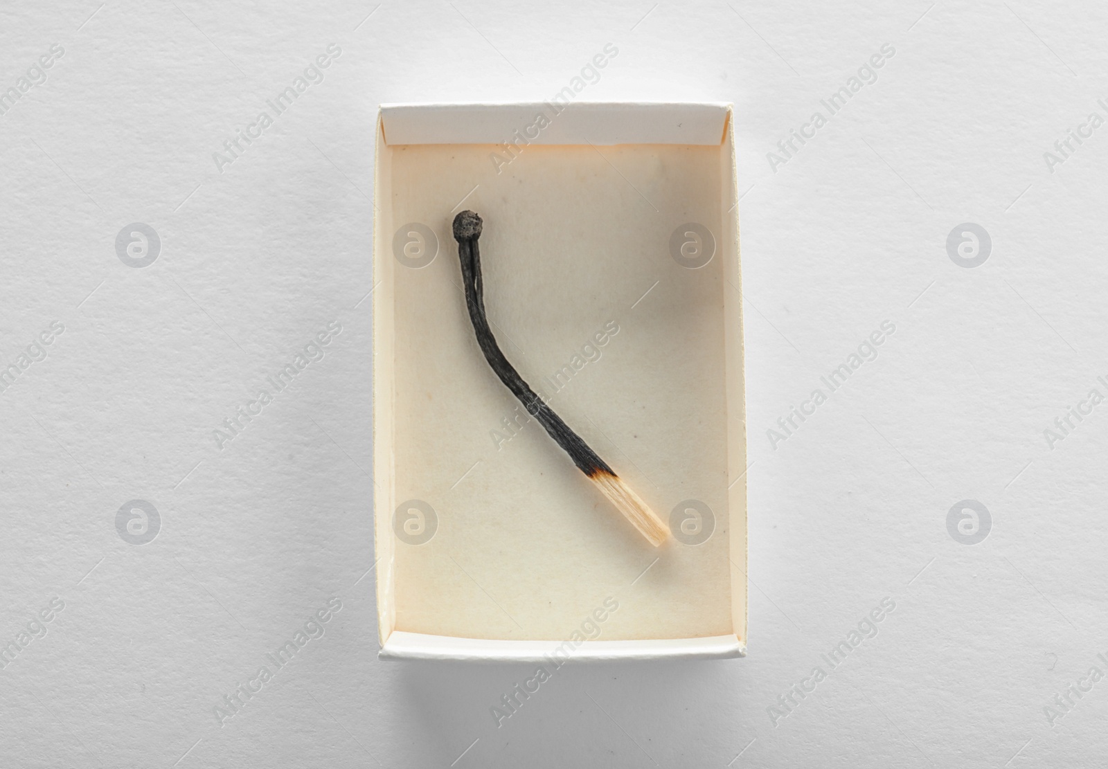 Photo of Cardboard box with burnt match on white background, top view