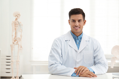 Photo of Handsome orthopedist sitting at table in office