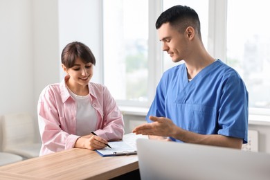 Smiling medical assistant working with patient at hospital reception