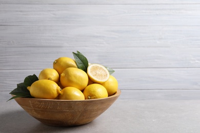 Photo of Many fresh ripe lemons on light grey table, space for text