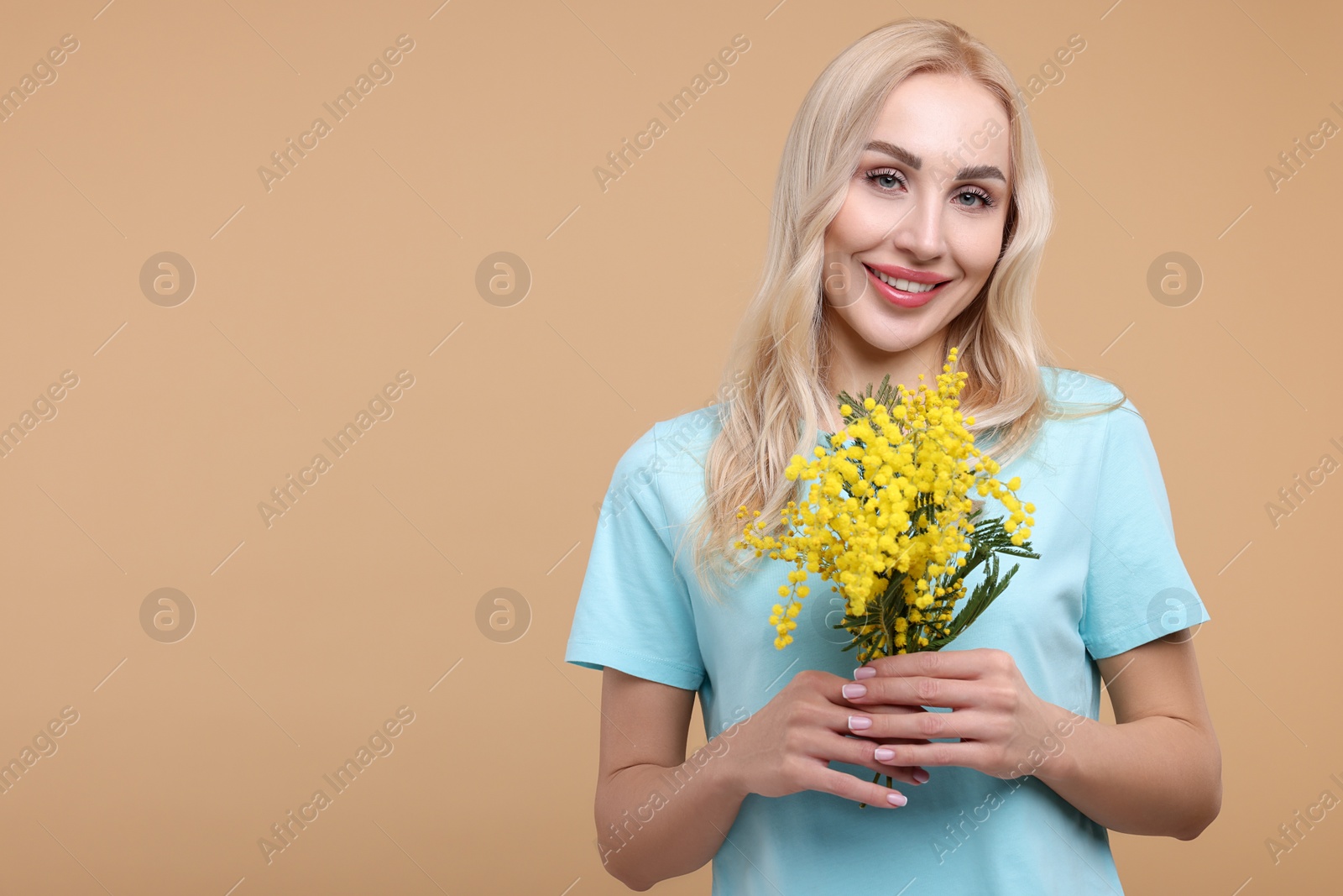 Photo of Happy young woman with beautiful bouquet on beige background. Space for text