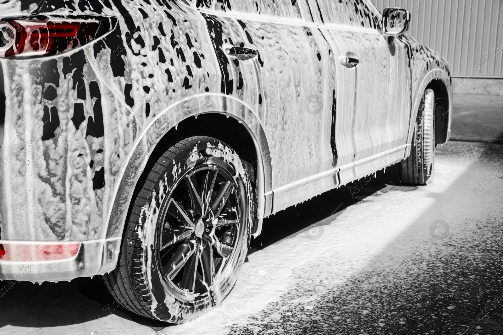 Photo of Luxury automobile covered with foam at car wash, closeup