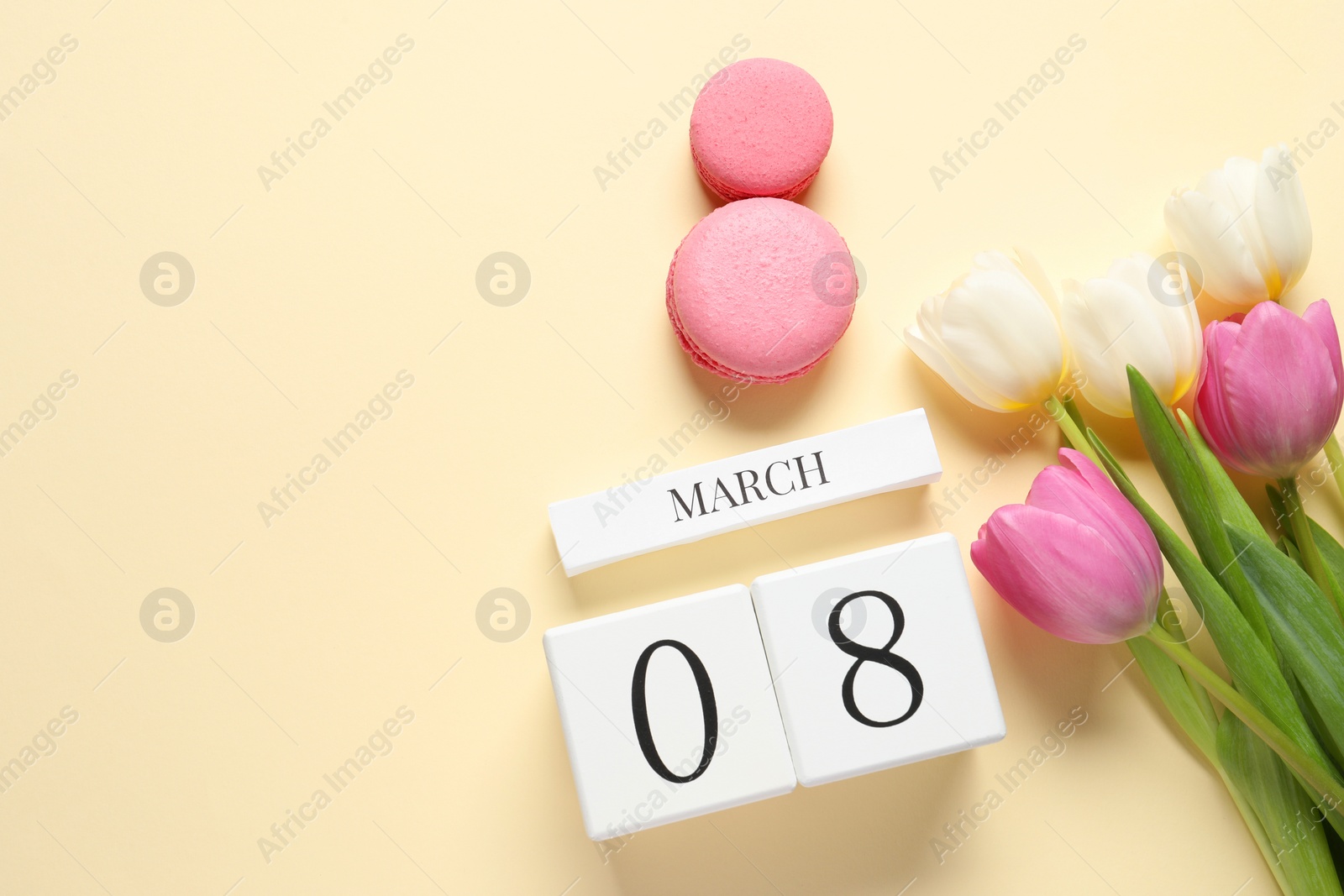 Photo of International Women's day - 8th of March. Macaron cookies, wooden block calendar and beautiful flowers on beige background, flat lay. Space for text