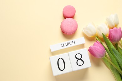 Photo of International Women's day - 8th of March. Macaron cookies, wooden block calendar and beautiful flowers on beige background, flat lay. Space for text