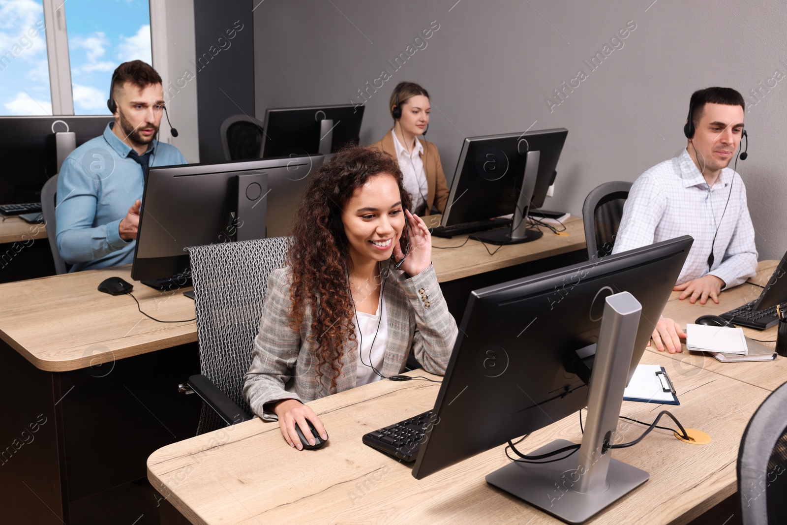 Photo of Call center operators with headsets working in modern office