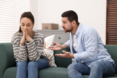 Photo of Offended wife ignoring her angry husband indoors. Relationship problems