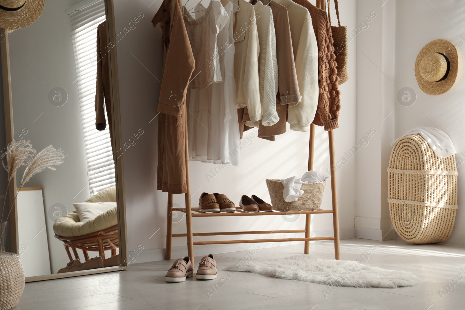 Photo of Rack with stylish women's clothes in dressing room. Modern interior design