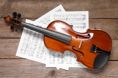 Photo of Violin and music sheets on wooden table, top view