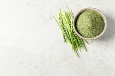 Photo of Wheat grass powder in bowl and fresh sprouts on light table, flat lay. Space for text