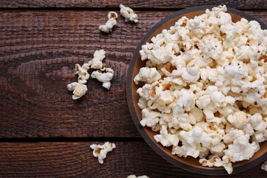 Bowl of tasty popcorn on wooden table, flat lay. Space for text