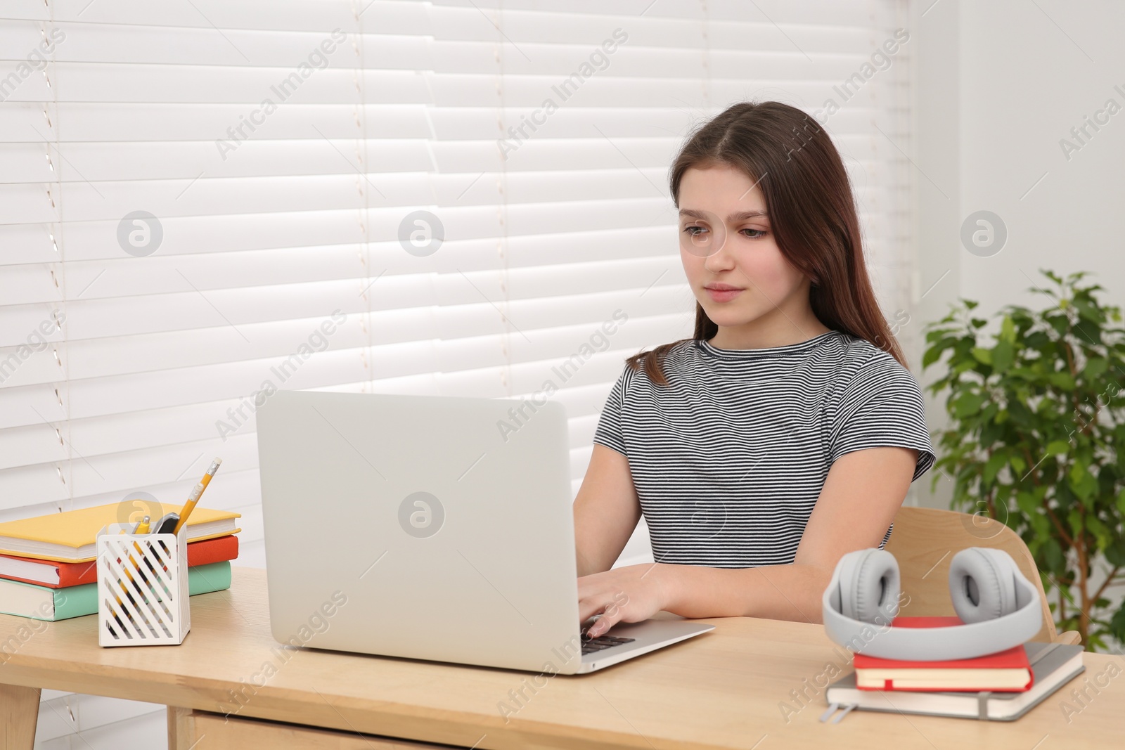 Photo of Cute girl using laptop at desk in room. Home workplace