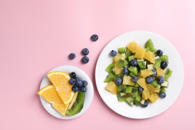 Plate of tasty fruit salad and ingredients on pink background, flat lay