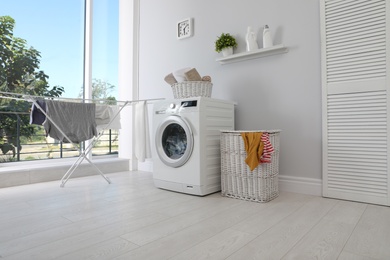 Photo of Laundry room interior with washing machine near wall