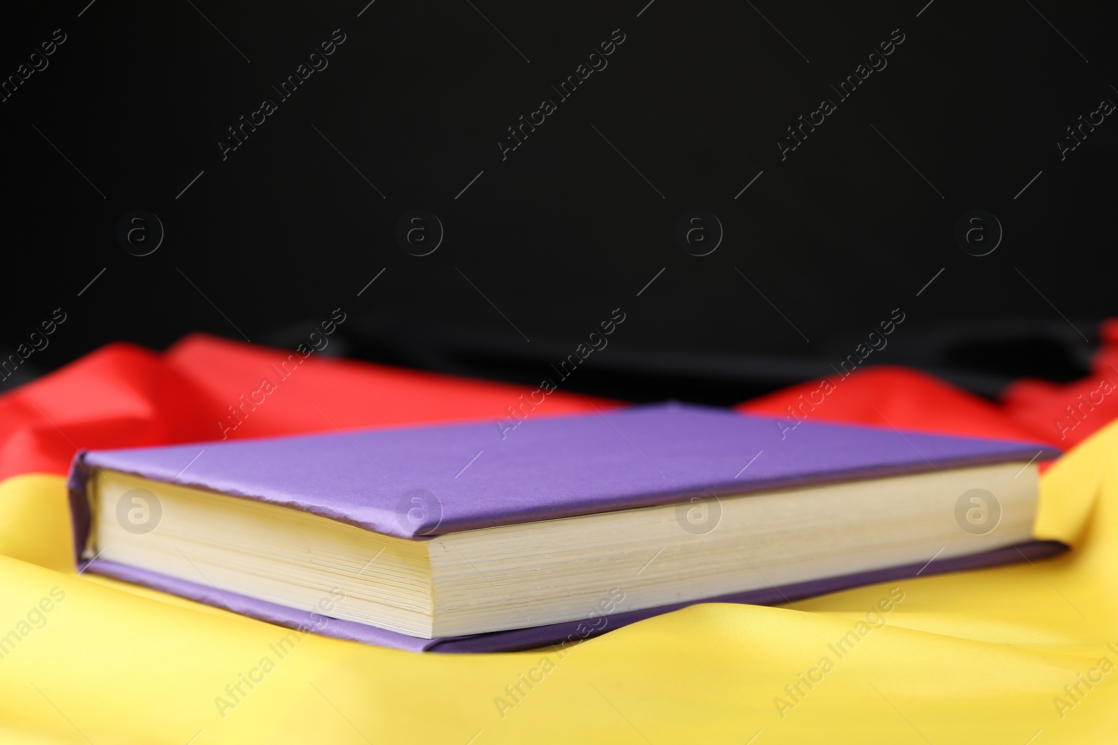 Photo of Learning foreign language. Book on flag of Germany, space for text