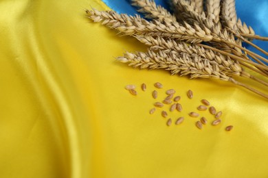 Photo of Ears of wheat and grains on Ukrainian national flag, closeup. Space for text