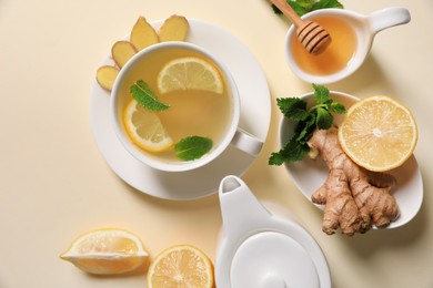 Photo of Delicious ginger tea and ingredients on beige background, flat lay
