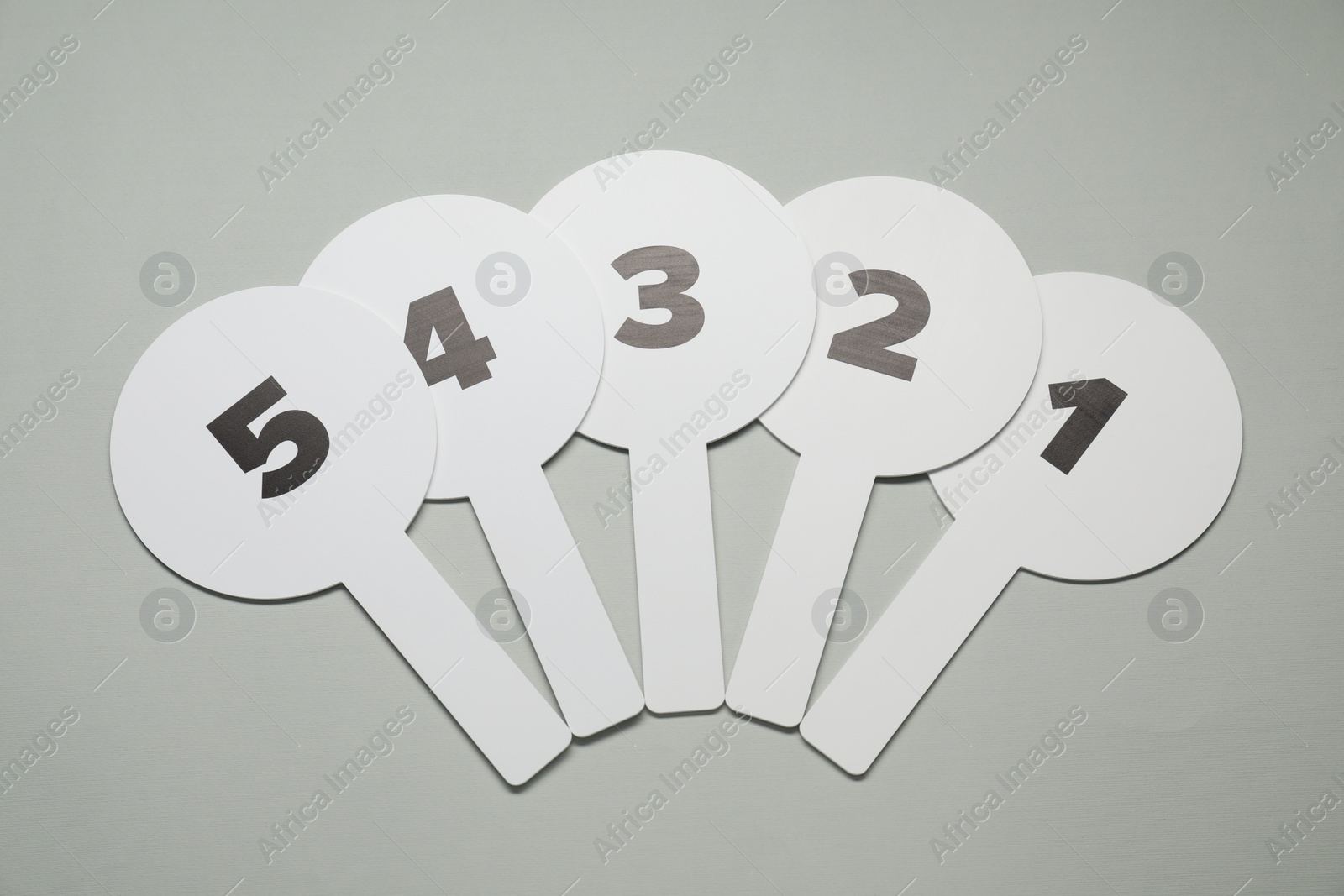 Photo of Auction paddles with numbers on light grey background, flat lay