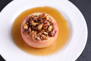 Photo of Tasty baked apple with nuts and honey on gray table, closeup