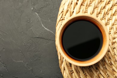 Soy sauce in bowl on black textured table, top view. Space for text