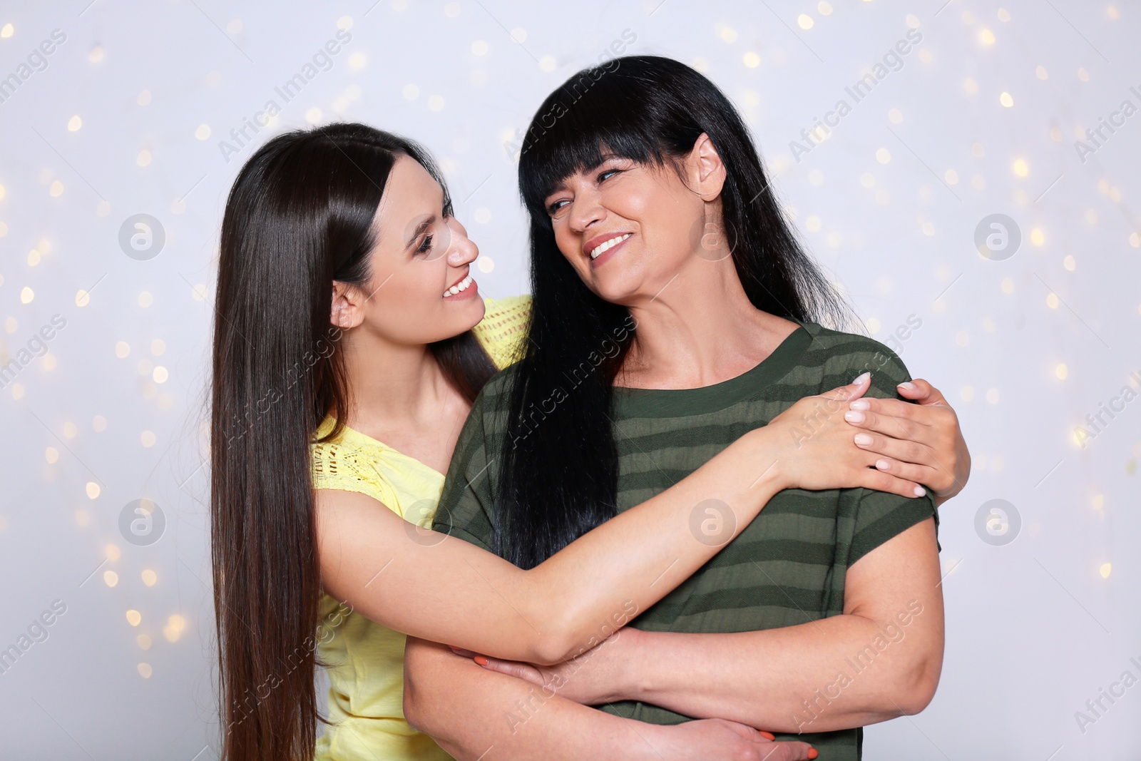 Photo of Portrait of young woman and her mature mother against defocused lights